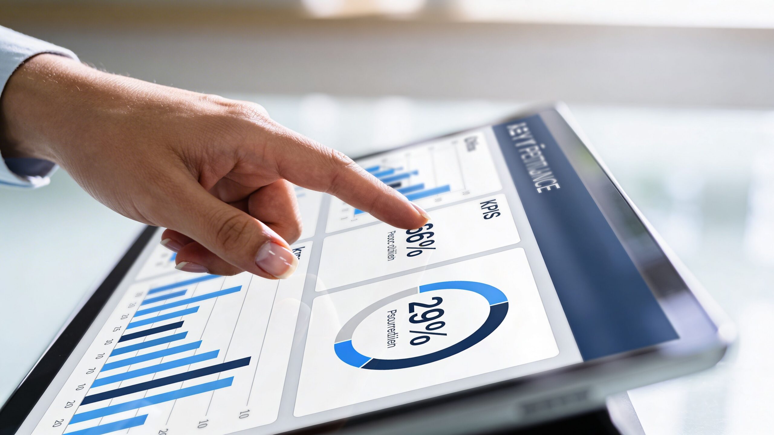 Une personne utilisant une tablette tactile pour analyser des indicateurs de performance et des graphiques financiers.